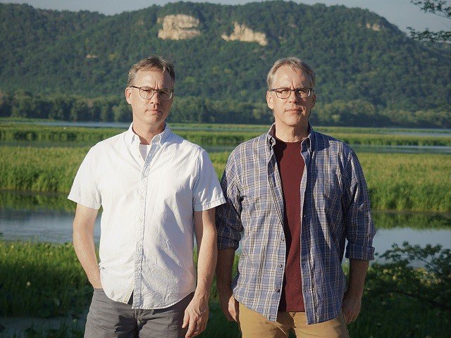 The members of Spartz Electric in front of a hill and lake.