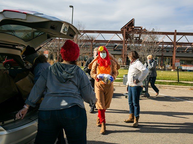 A person in a turkey suit carrying a turkey.