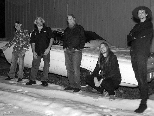 Five people standing in front of a vintage car.