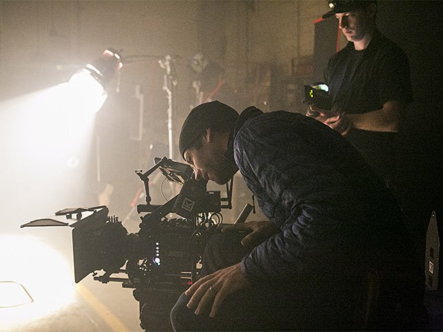 A man looking into a complicated motion picture camera.