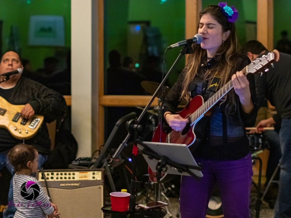 Angela Puerta playing guitar and singing.