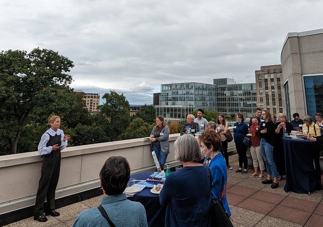 People on a Capitol Square rooftop deck gathering to listen to Jane Rotonda.