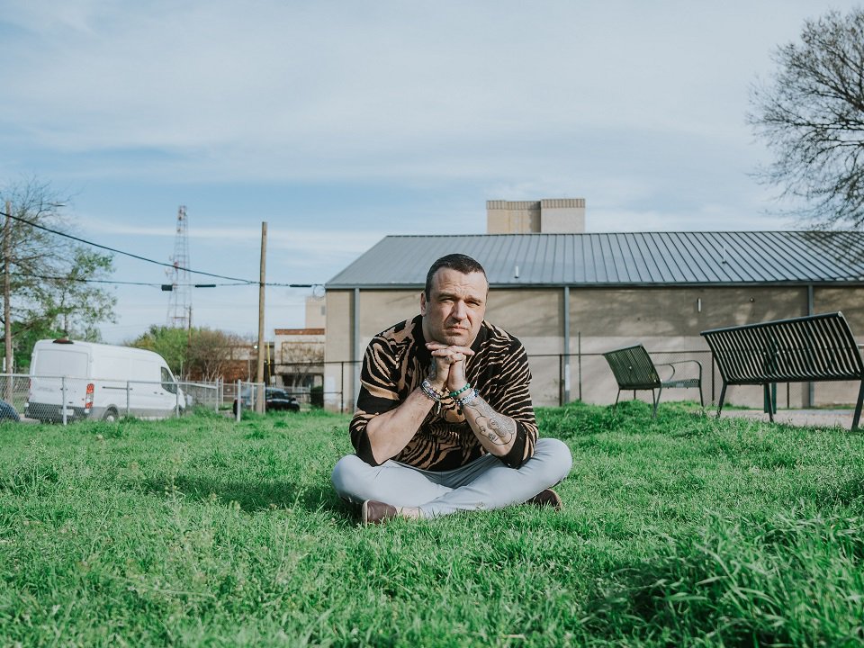 Max Bemis of the band Say Anything sitting on the grass.