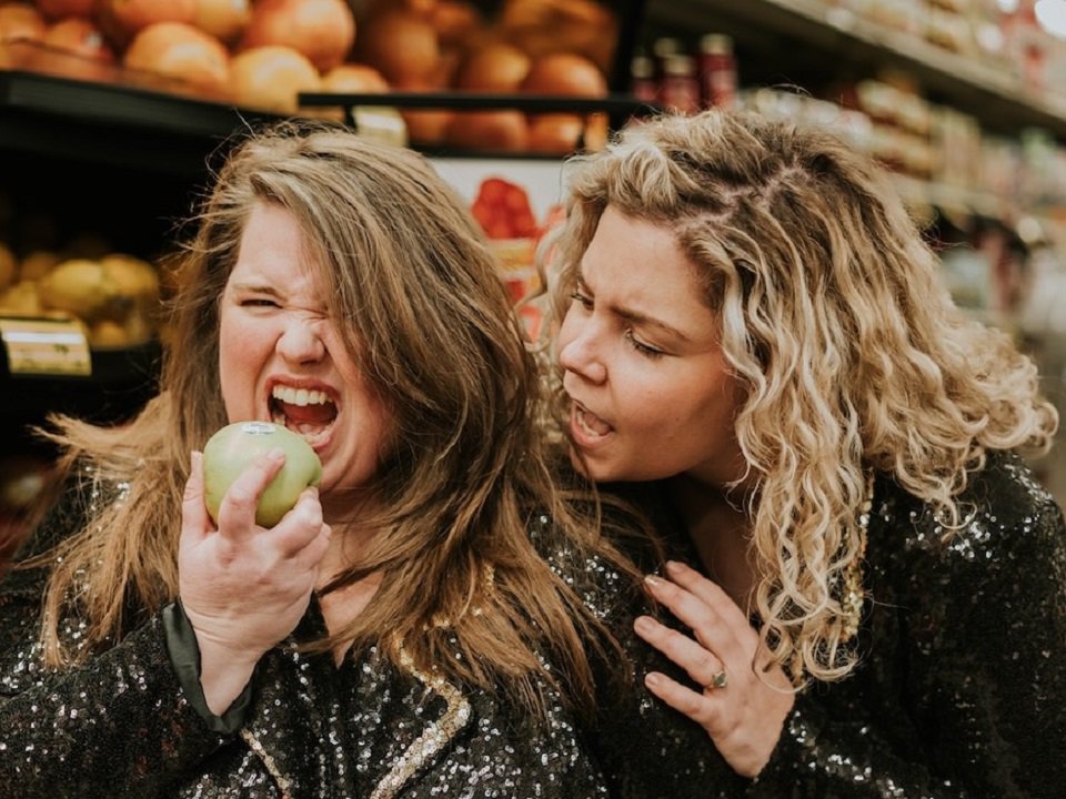 Louisa Hall (left) and  Annie Nardolilli of Griefcat prepare to bite an apple.