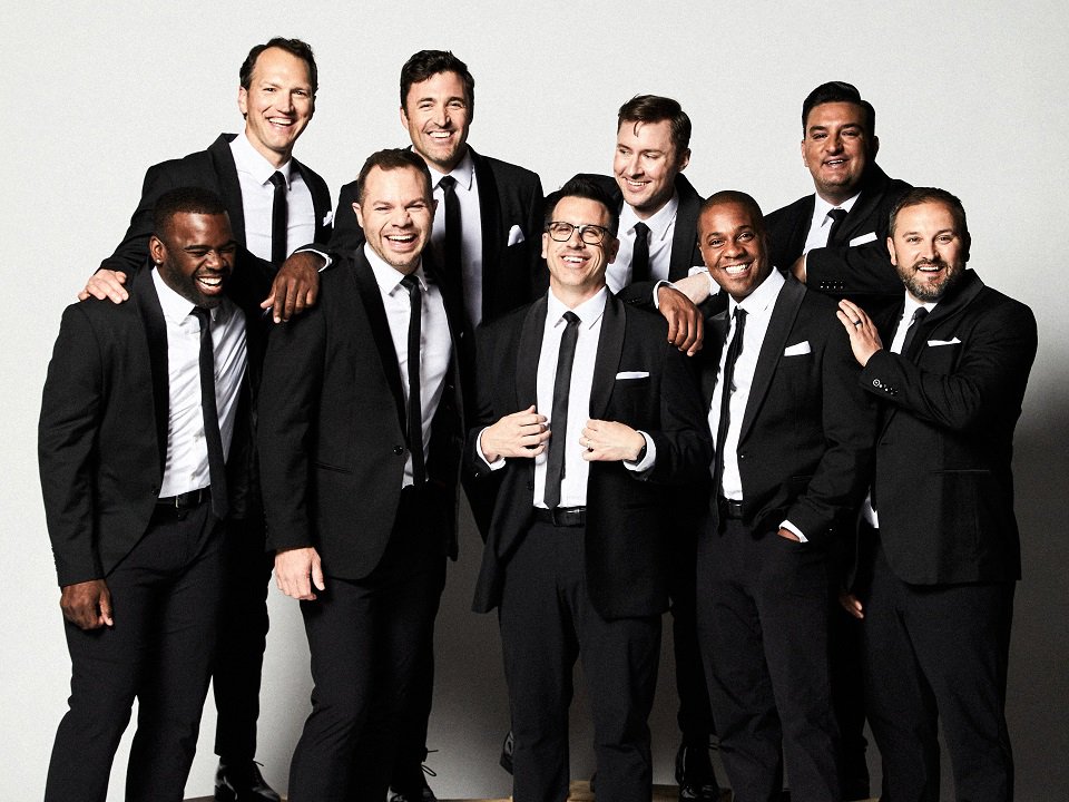 The nine members of Straight No Chaser wearing suits.