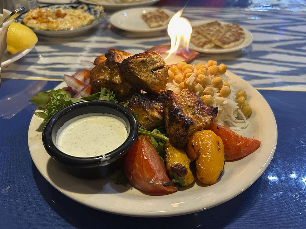 Very full platter of food with roast peppers and chunks oc chicken and a white dipping sauce.