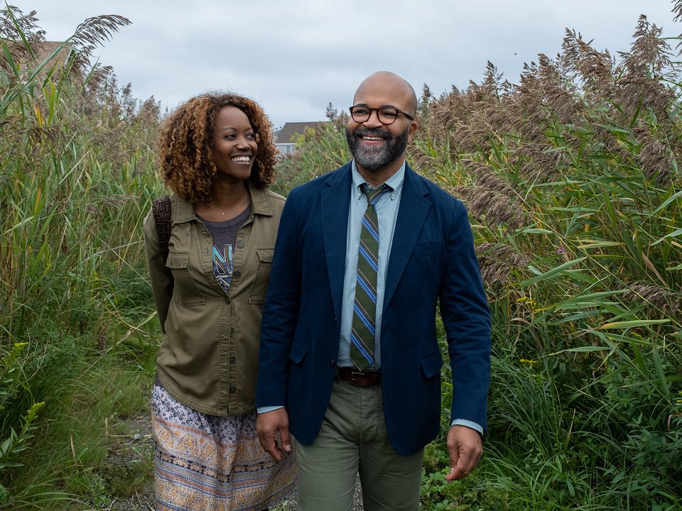 Two people walking on a path through tall grasses.