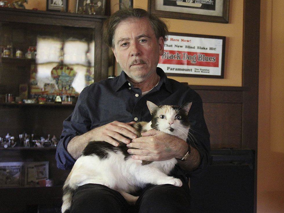 Film director Terry Zwighoff with a black and white cat in his lap.