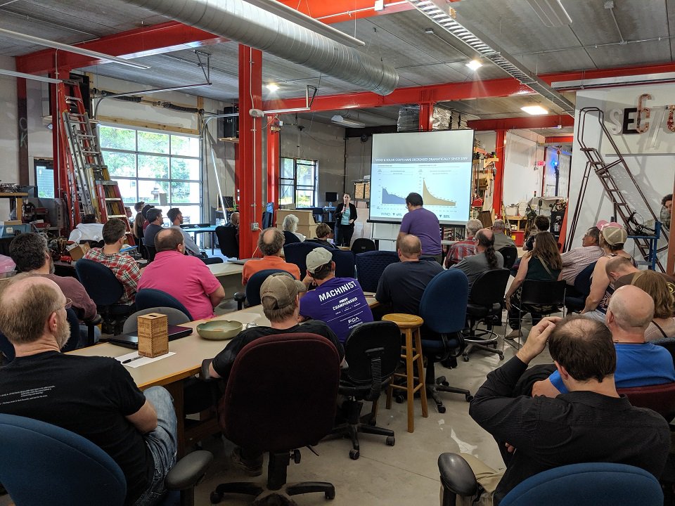 A group of people watch a presentation.