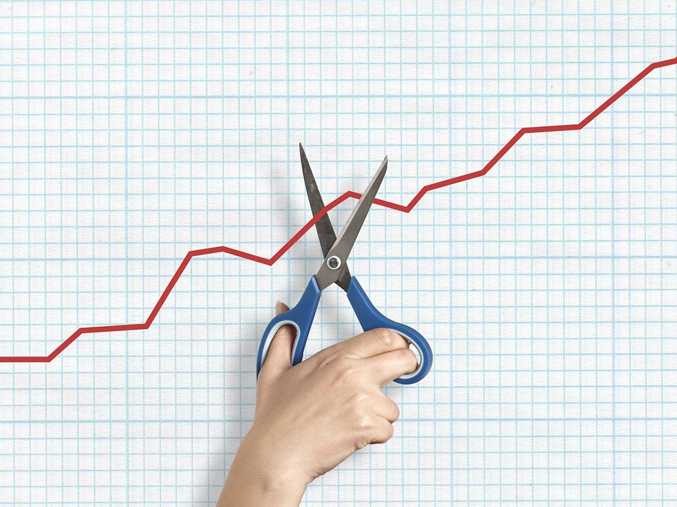 A pair of scissors cutting a line graph.