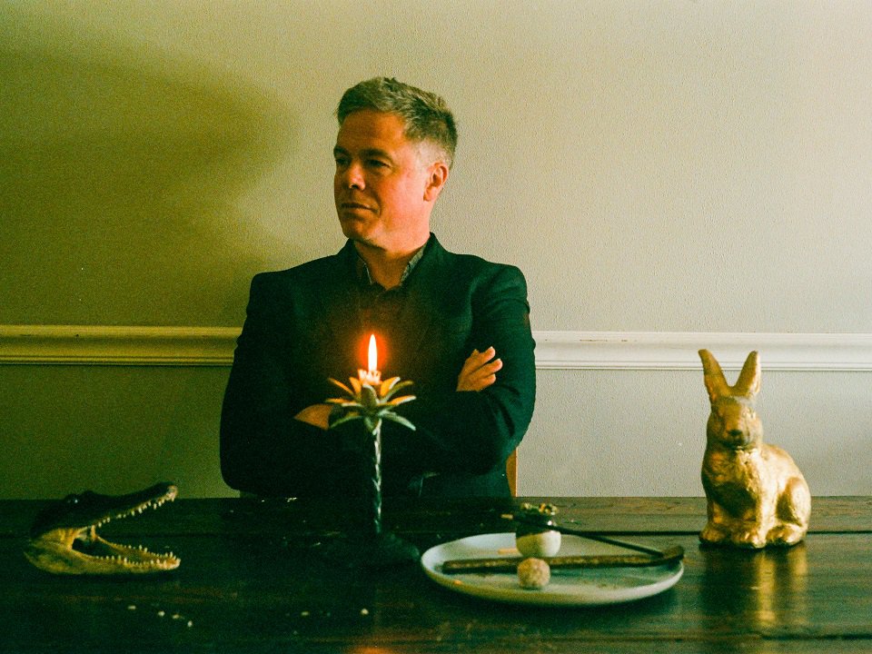 Josh Ritter sitting at a table with an alligator head and rabbit.