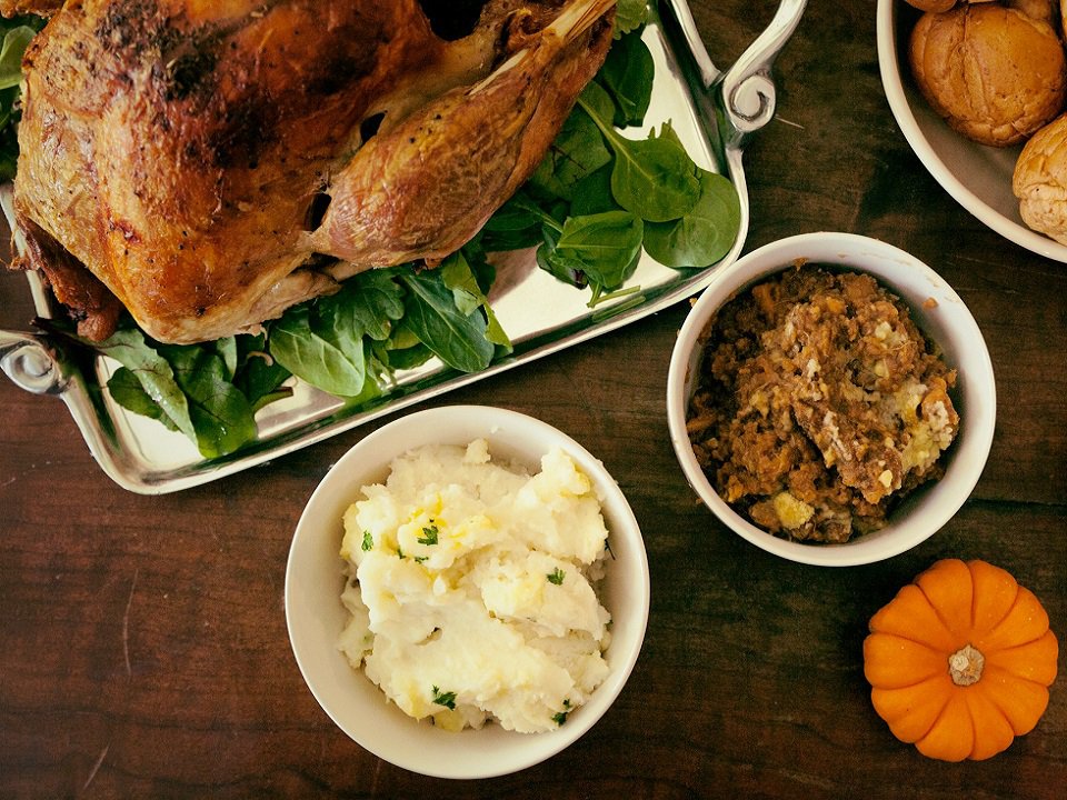 A roast turkey, mashed potatoes, stuffing and rolls.