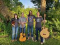 The four members of Tumbledown Shack and instruments in the woods.
