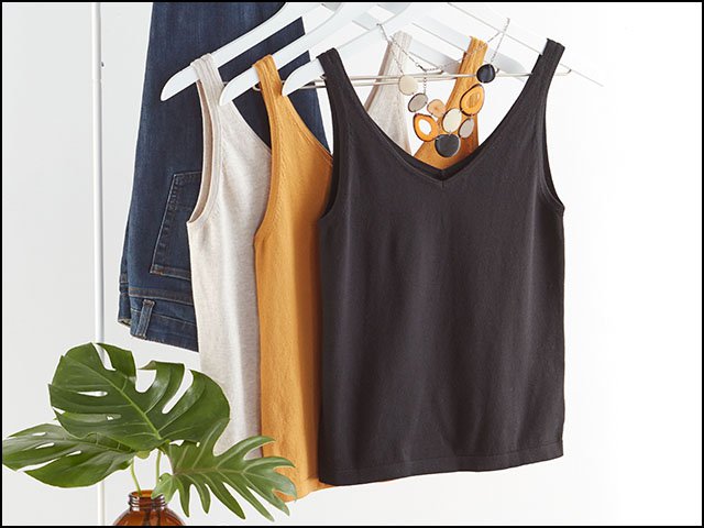 Three tank tops, in black, white, and golden yellow are on hangers. 