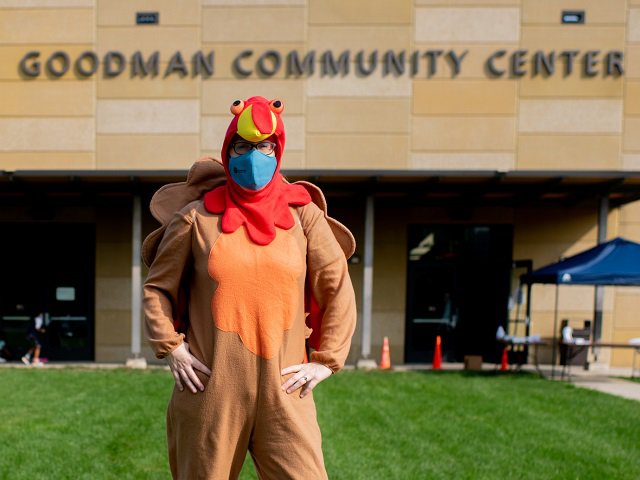 A person in a turkey costume in front of Goodman Community Center.