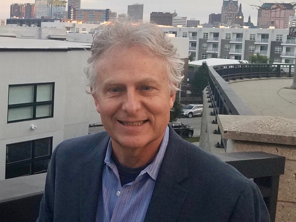 A close-up of Jeffrey D. Boldt against a city skyline.