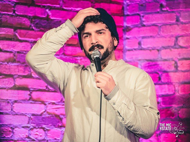 Stand-up comedian David Louis in front of a pink wall.