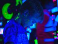 A child creates art in a black light room.