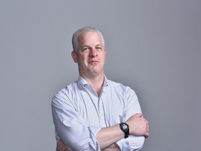 Journalist Craig Whitlock in front of a gray background.