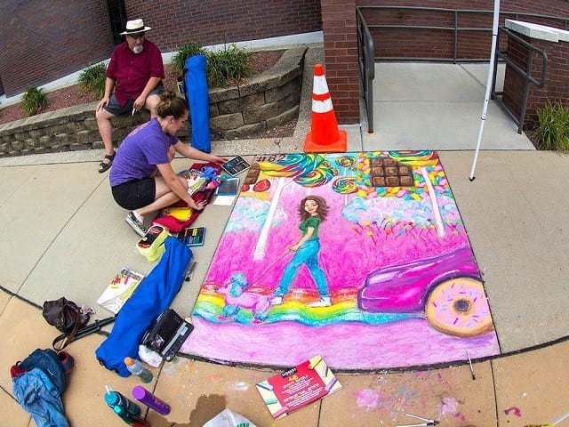 A sidewalk chalk artist creates a mural.
