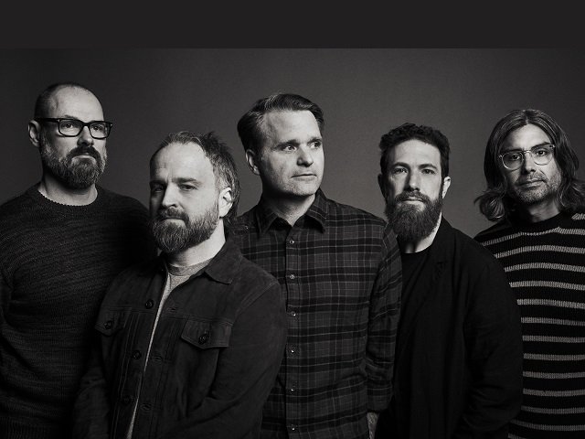The five members of Death Cab for Cutie against a gray background.