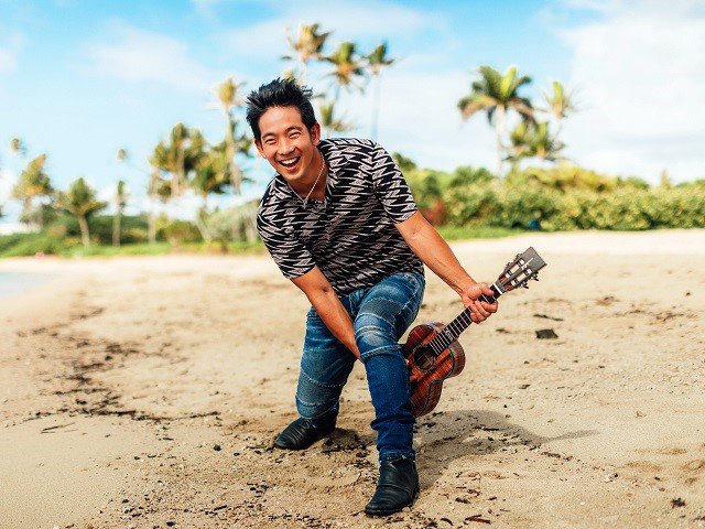 Jake Shimabukuro on the beach with ukulele.