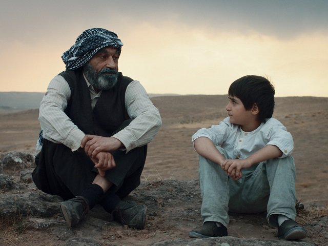 A man and boy sit on the ground.