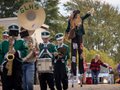 A marching band, scarecrow stilt walker and others in a Harvest Fest parade.