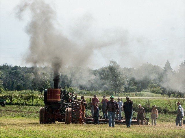 A vintage tractor makes some smoke.