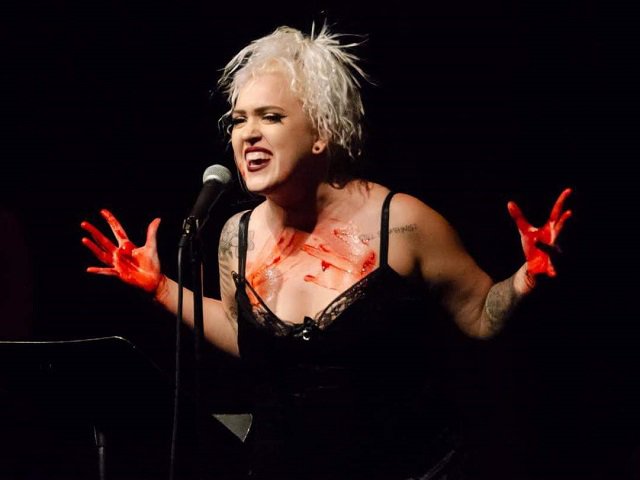 Burlesque artist Helena Havok on stage with red-covered hands.