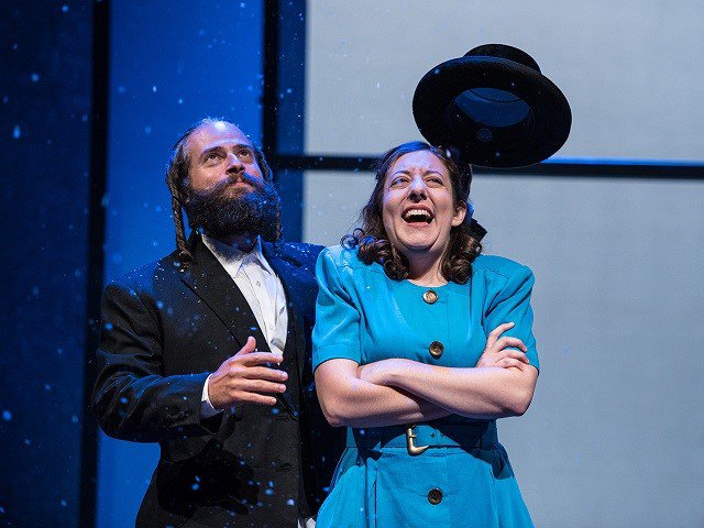 A man in a suit, a woman in a blue dress and a black hat thrown in the air.