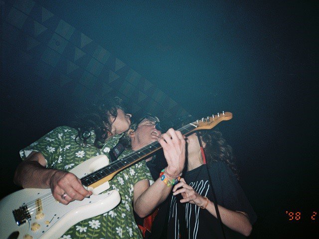 Three members of The Wrecks around a mic.