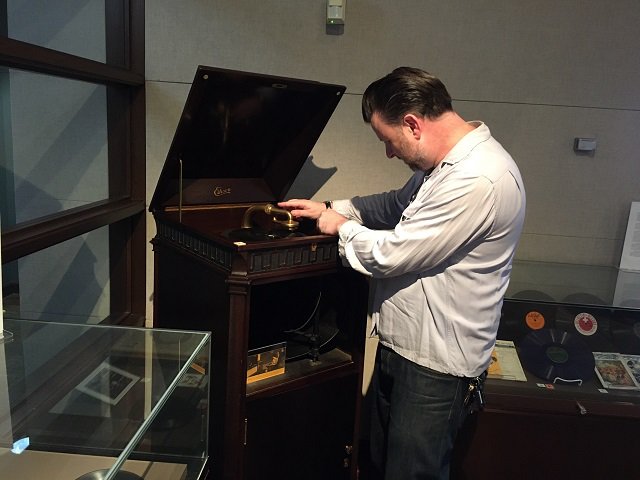 A man playing a record on an Edison phonograph.