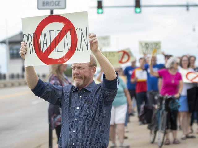 A man holds a sign against privatization.