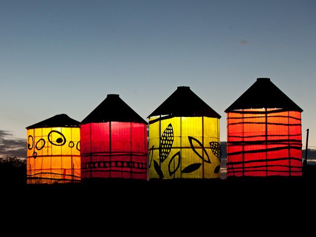 Colorful corn cribs against a dusk sky.