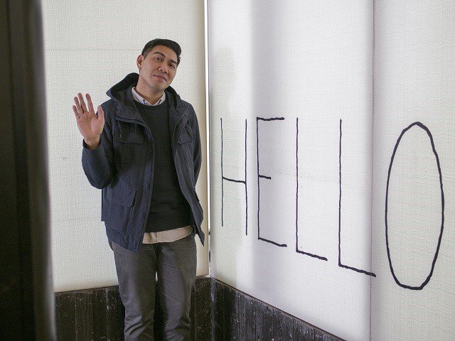 A person standing in front of a sign saying HELLO.