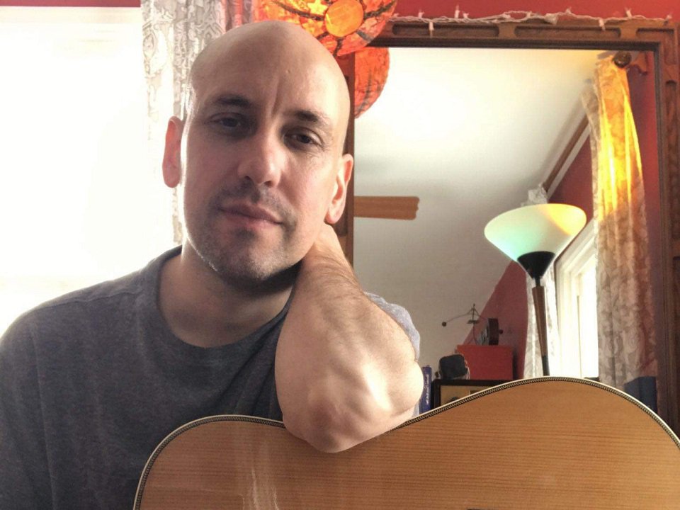 A man leans on a guitar.