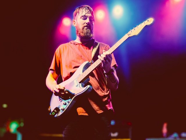 A person on stage with a guitar.