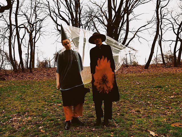 Two people in costumes in a fall landscape.