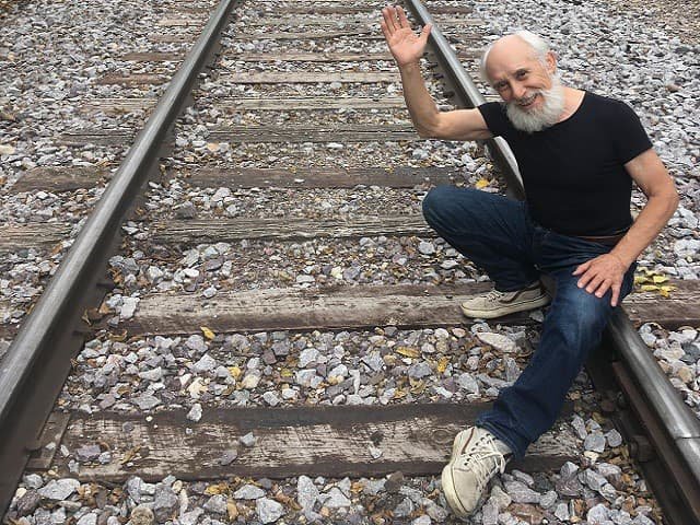 A person waving on a set of railroad tracks.