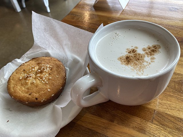 A small sweet cake and a chai latte in a white cup.