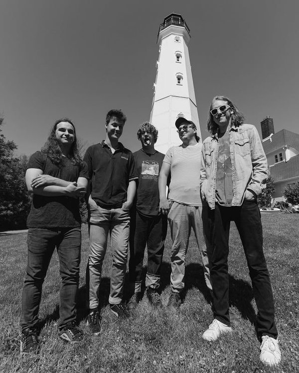 Five people standing in front of a lighthouse.