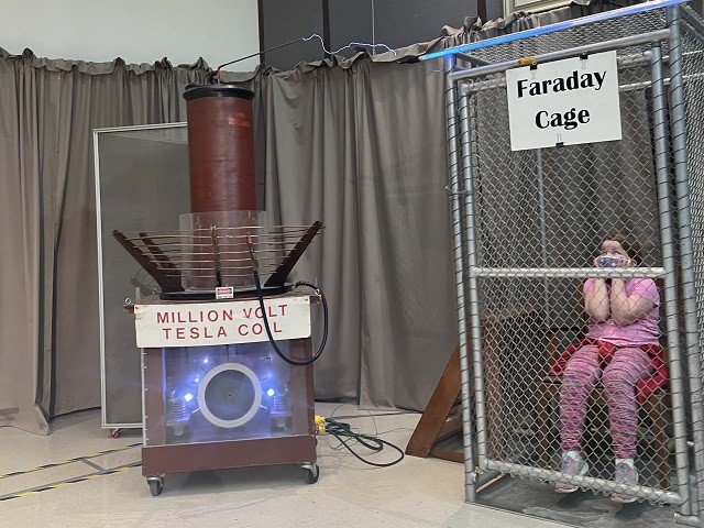 A Tesla coil and a person in a wire cage.