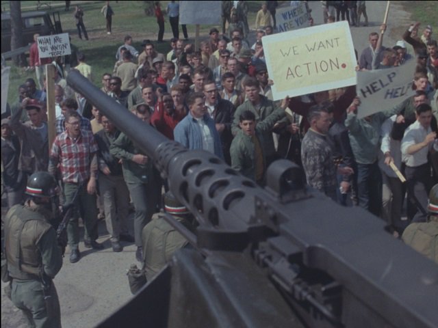 A military weapon is trained on a crowd of protesters.