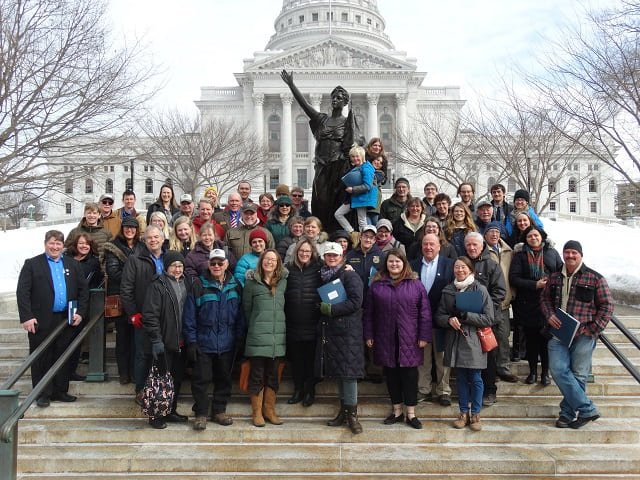 A group of people standing by the "Forward" statue at the Wisconsin Capitol.