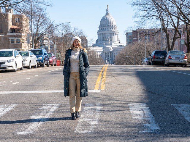 A person in the middle of the street with the Wisconsin Capitol in the background.