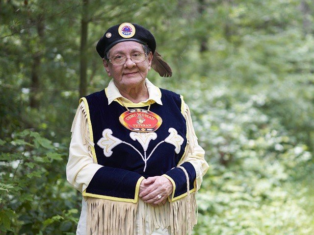 A person poses for a photo in the woods.