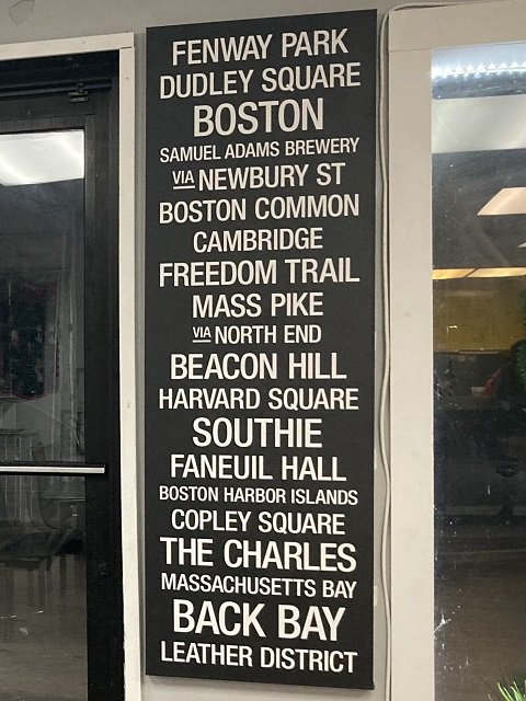 Black and white signboard listing tourist sites in Boston.