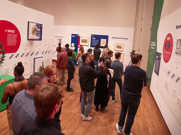 Persons looking at a timeline in an art gallery.
