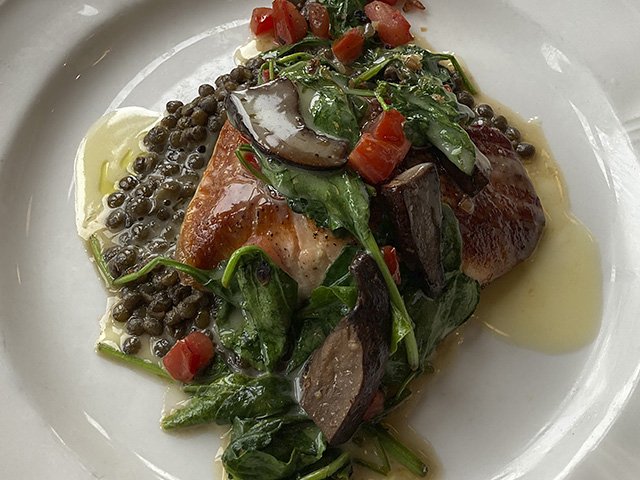 Seared salmon on a plate with spinach, lentils and portobello mushrooms.